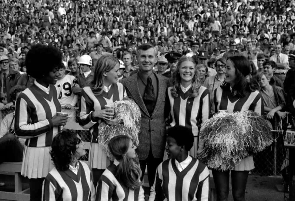 Johnny Carson standing with cheerleaders at football game in 1971