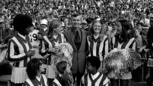 Johnny Carson standing with cheerleaders at football game in 1971