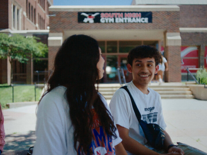 Students talking while sitting outside high school entrance